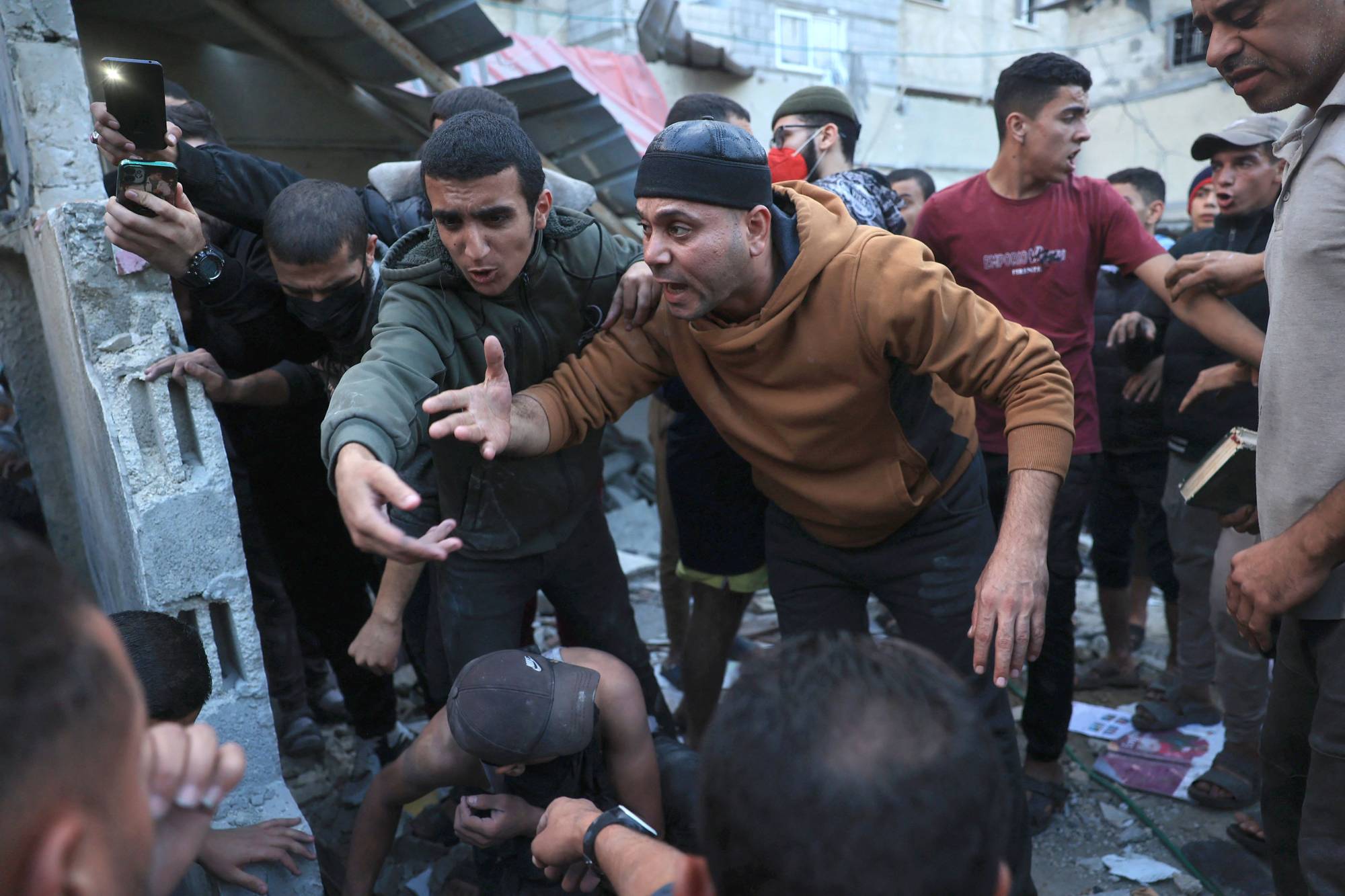 رد فعل الفلسطينيين بينما يعمل المسعفون على إنقاذ رجل من أنقاض مبنى بعد القصف الإسرائيلي في رفح بجنوب قطاع غزة (أ.ف.ب)