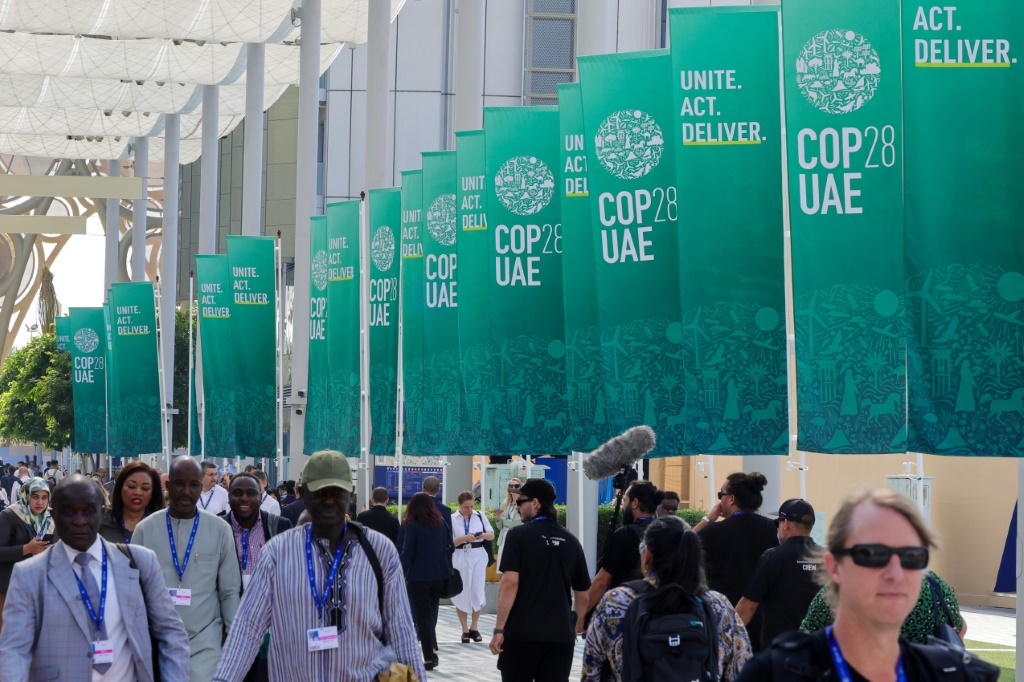 مشاركون يسيرون أمام لافتات في قمة الأمم المتحدة للمناخ كوب28في دبي في 3 كانون الأول/ديسمبر 2023 (ا ف ب)