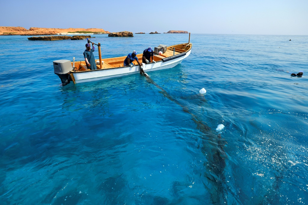 أشخاص يسحبون شباك الصيد التي أزالها الغواصون من الشعاب المرجانية في جزر الديمانيات العمانية في الرابع من تشرين الأول/أكتوبر 2024 (ا ف ب)
