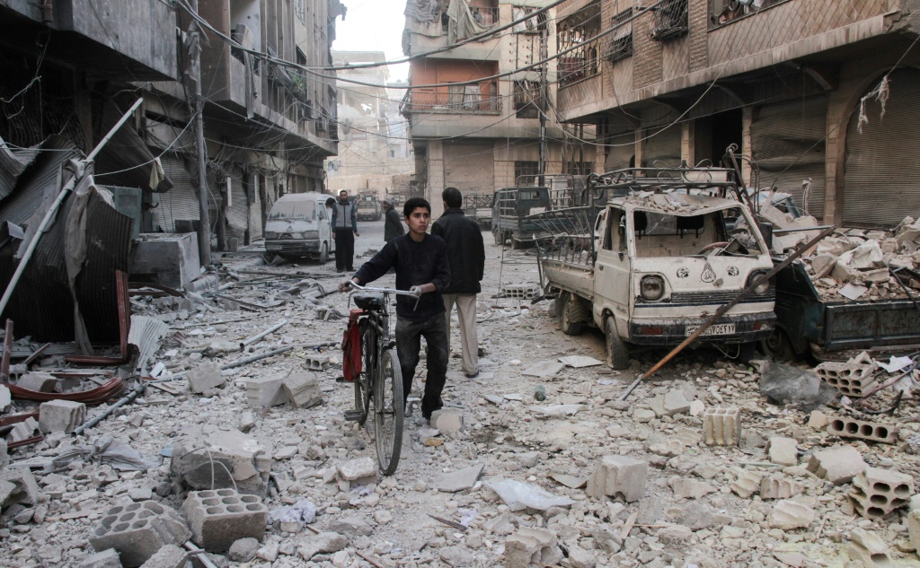 فتى يجر دراجة هوائية في شارع وسط الدمار الذي خلفه قصف للحكومة السورية، بحسب تقارير، في دوما بتاريخ 17 تشرين الثاني/نوفمبر 2017 (ا ف ب)