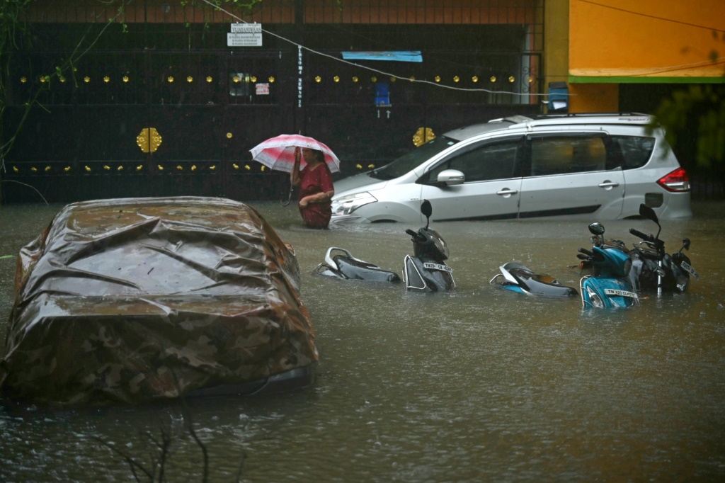 أحد السكان يتجول في شارع غمرته المياه بعد هطول أمطار غزيرة في تشيناي في 4 ديسمبر (ا ف ب)