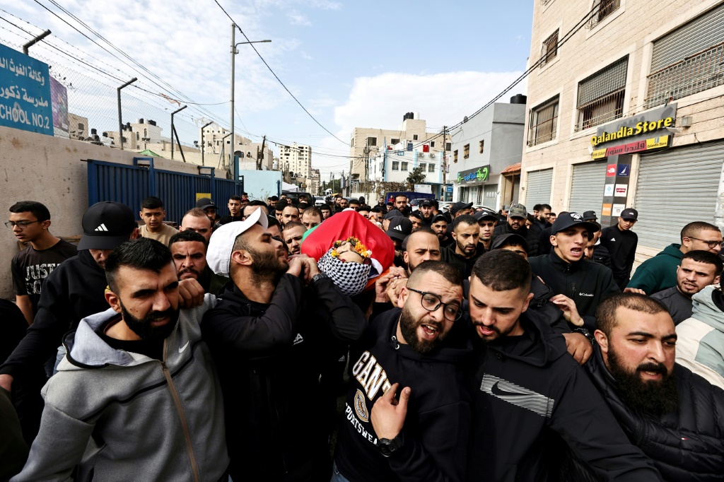مشيعون يحملون جثمان الشاب محمد مناصرة (25 عاما) الذي قتل بعد اقتحام الجيش الإسرائيلي منزل عائلته في مخيم قلنديا للاجئين الفلسطينيين شمال القدس في الخامس من كانون الأول/ديسمبر 2023 (أ ف ب)   