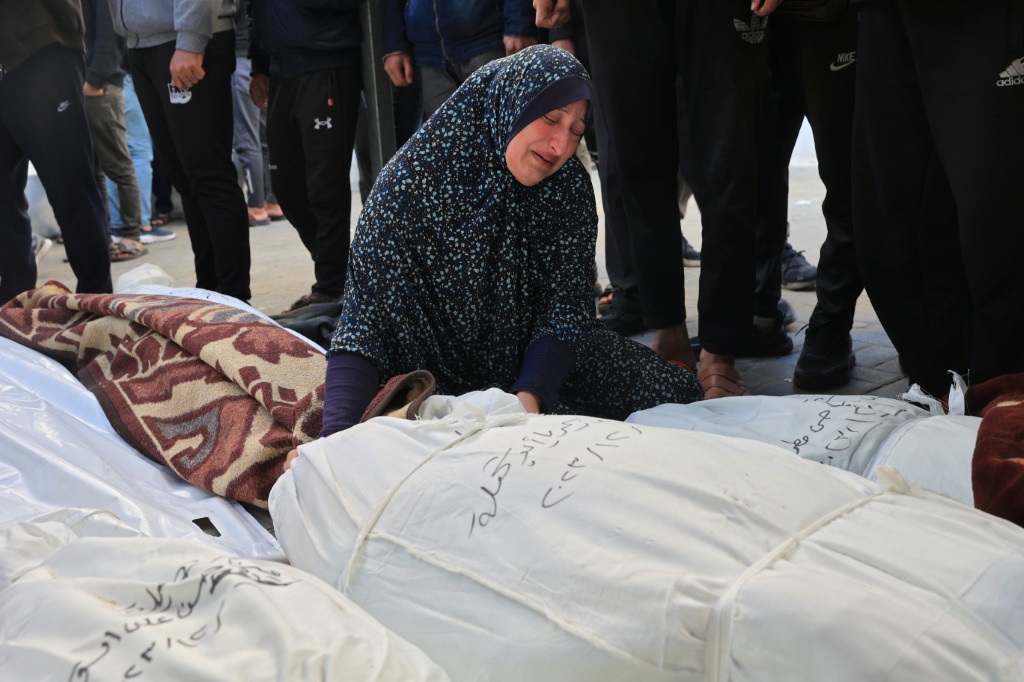 امرأة تبكي فوق جثث أفراد عائلتها الذي قتلوا في غارة إسرائيلية في مستشفى النصر في رفح بجنوب قطاع غزة في 7 كانون الأول/ديسمبر 2023 (ا ف ب)
