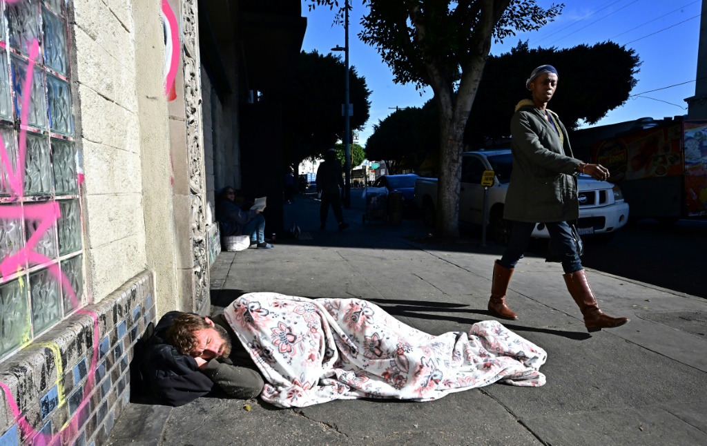 رجل بلا مأوى ينام على الرصيف في لوس أنجلوس، كاليفورنيا في 22 نوفمبر 2023 – واحد من الآلاف الذين فعلوا ذلك (أ ف ب)   