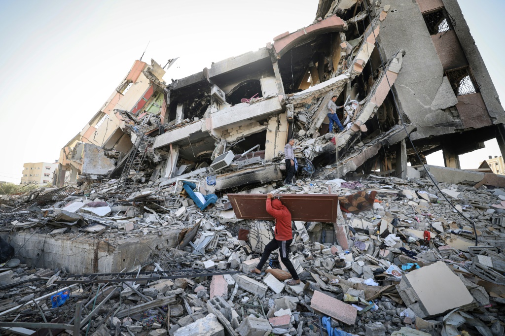 فلسطينيون يحملون بعض مقتنياتهم يسيرون وسط أنقاض المباني المدمرة في حيّ الزهراء بالضواحي الجنوبية لمدينة غزة في 26 تشرين الثاني نوفمبر 2023 مع دخول الهدنة بين إسرائيل وحماس يومها الثالث (ا ف ب)
