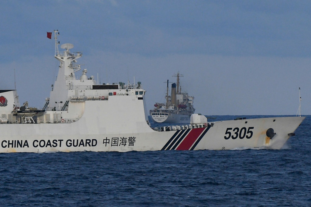 صورة ملتقطة في 10 كانون الأول/ديسمبر 2023 تظهر سفينة لخفر السواحل الصيني (وسط) تبحر على مقربة من سفينة فيليبينية في بحر الصين الجنوبي (ا ف ب)