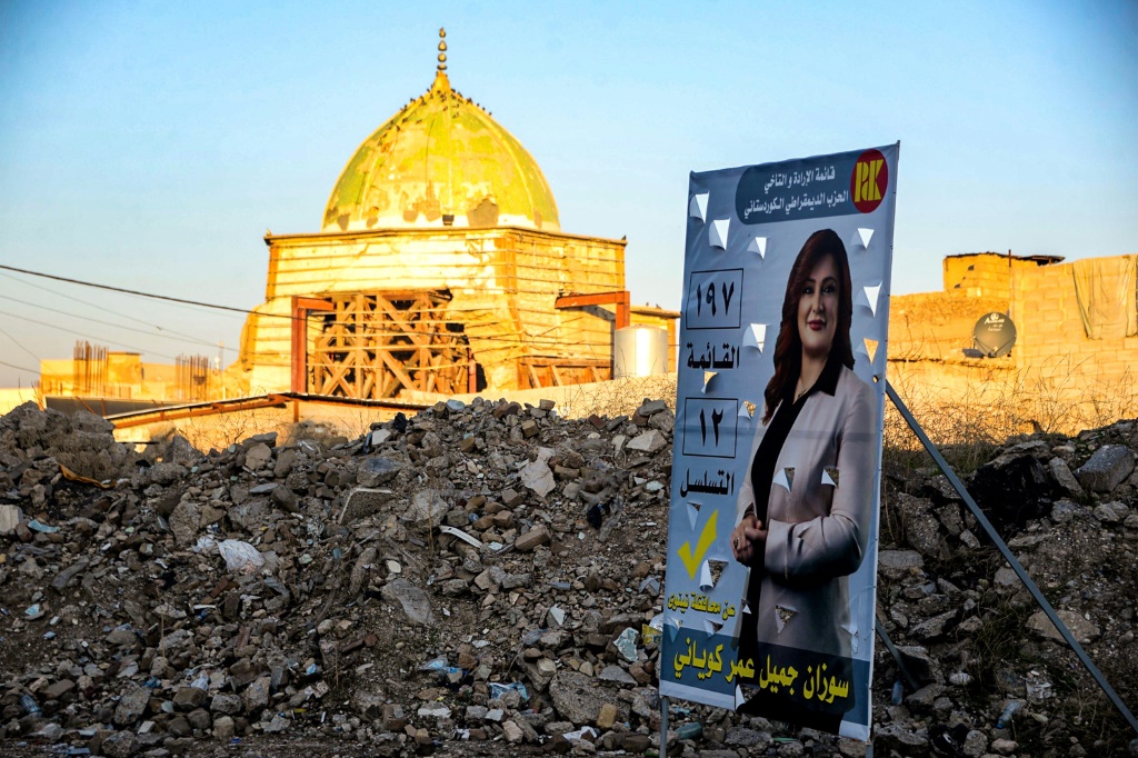 صورة للمرشح في الانتخابات المحلية البرازيلية أمام ركام في المدينة القديمة في الموصل في 17 كانون الأول/ديسمبر 2023 (ا ف ب)