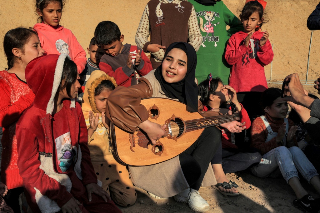 رؤى حسونة تعزف الموسيقى للأطفال الفلسطينيين في مخيم للنازحين في رفح في 18 كانون الأول/ديسمبر 2023 (ا ف ب)