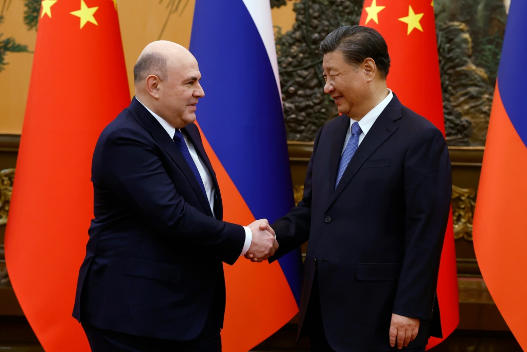 رئيس الوزراء الروسي ميخائيل ميشوستين (يسار) والرئيس الصيني شي جين بينغ يتصافحان قبل اجتماعهما يوم الأربعاء في بكين (أ ف ب)   