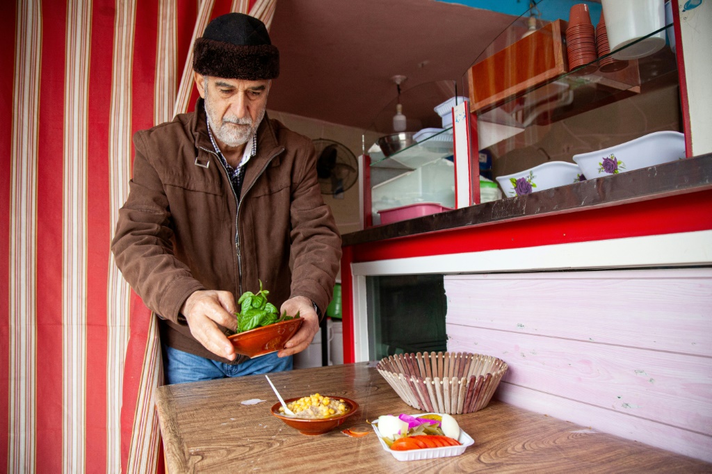 اللبناني حسين مرتضى يعد الطعام في مطعمه في بلدة كفركلا الحدودية مع إسرائل في 21 كانون الأول/ديسمبر 2023 (ا ف ب)