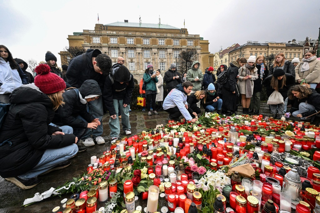 أشخاص يضعون الشموع والزهور أمام مبنى جامعة تشارلز في 22 كانون الأول/ديسمبر 2023 في براغ في جمهورية التشيك (ا ف ب)