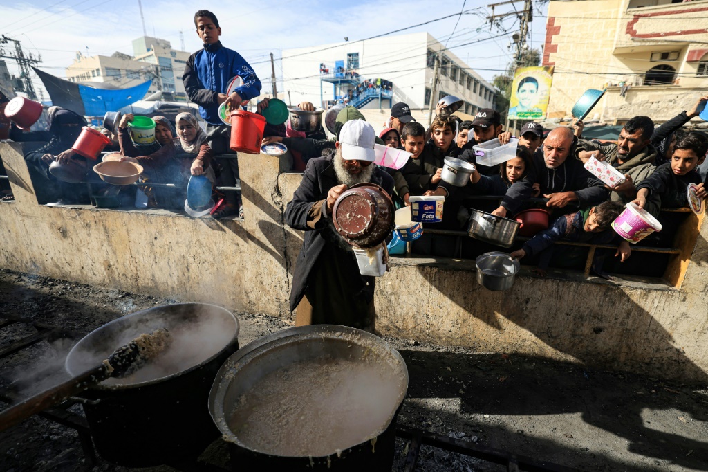 فلسطينيون يتسلمون وجبات طعام عند نقطة توزيع في مخيم رفح وغير ذلك في جنوب قطاع غزة في 23 الأول/ديسمبر 2023 (ا ف ب)