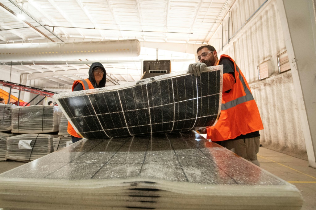 عاملان يحملان لوحا شمسيا قبل إعادة تدويره داخل مصنع في يوما بولاية أريزونا الأميركية في 6 كانون الاول/ديسمبر 2023 (أ ف ب)   