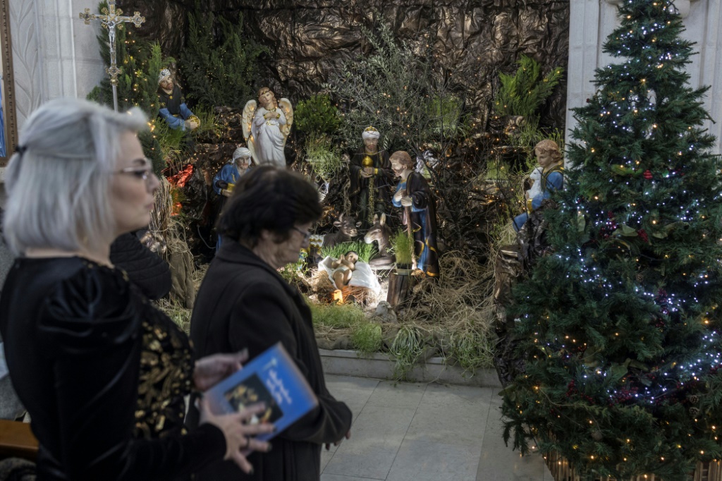 مؤمنون كاثوليك يصلون امام مغارة الميلاد في كنيسة الزيارة في بلدة الزبادبة في شمال الضفة الغربية المحتلة في 24 كانون الأول/ديسمبر 2023 (أ ف ب)   