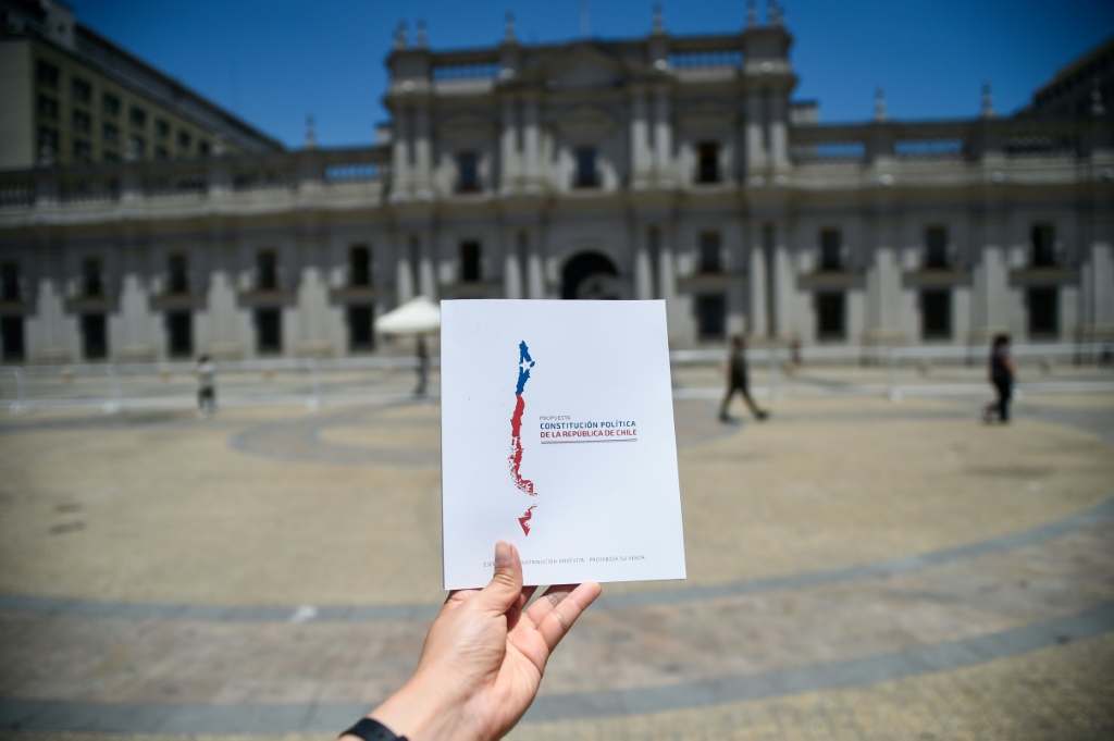 رجل يحمل نسخة من الدستور الجديد المقترح في تشيلي أمام قصر لا مونيدا الرئاسي ( ا ف ب)