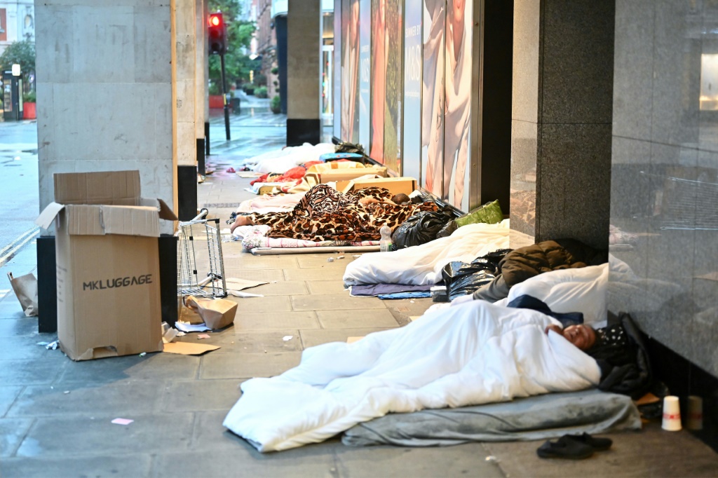 ينامون في أسرّتهم المؤقتة خارج المتاجر المغلقة، عند الفجر في شارع أكسفورد في لندن في 2 أغسطس 2023 (أ ف ب).   