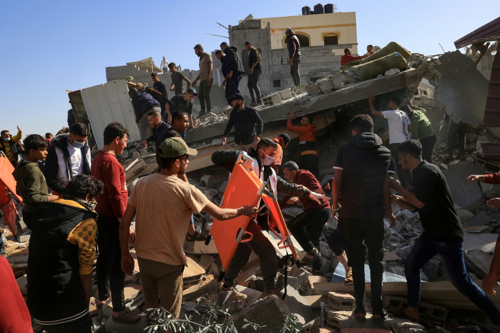 مسعف فلسطيني يسير بين المدنيين على أنقاض مبنى بعد غارة إسرائيلية على رفح، في جنوب قطاع غزة، في 23 تشرين الثاني نوفمبر 2023 (ا ف ب)