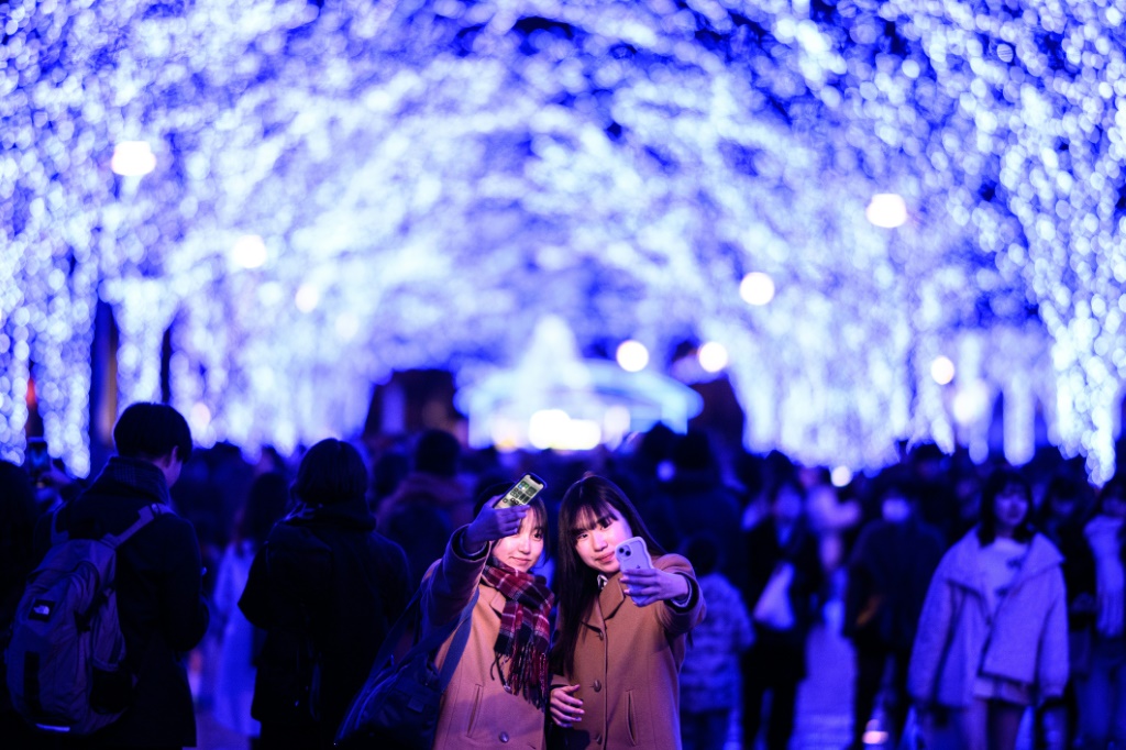 امراتان تلتقطان الصور في منقطة شيبويا في طوكيو في 21 كانون الاول/ديسمبر 2023 (ا ف ب)