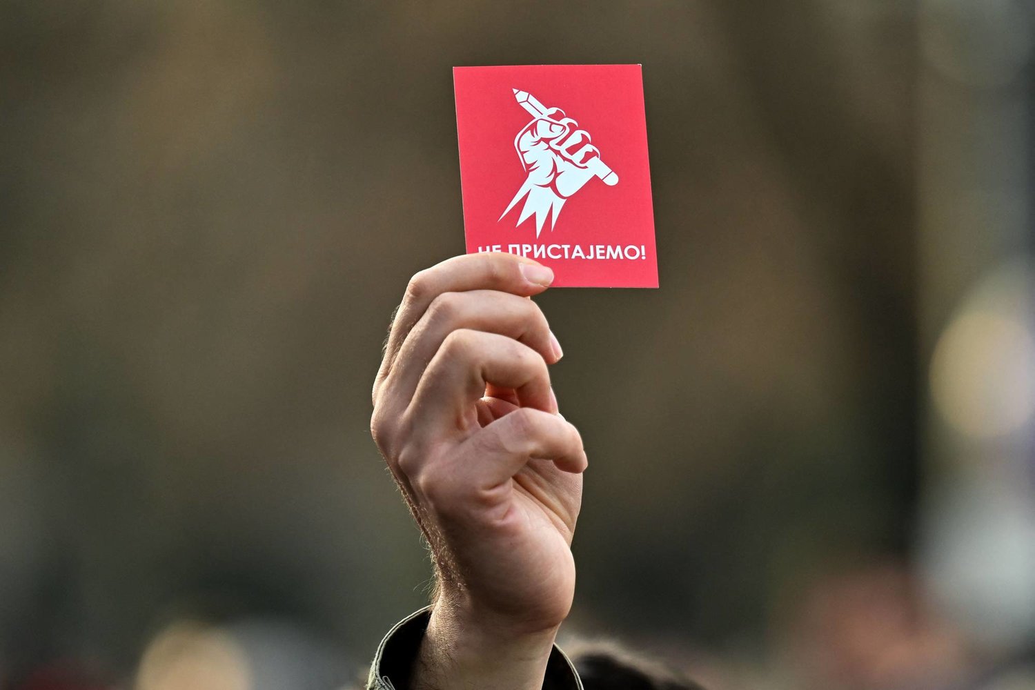 متظاهر صربي يحمل «كارت» أحمر كتب عليه «لا نقبل» في إشارة إلى رفض نتائج الانتخابات (أ.ف.ب)