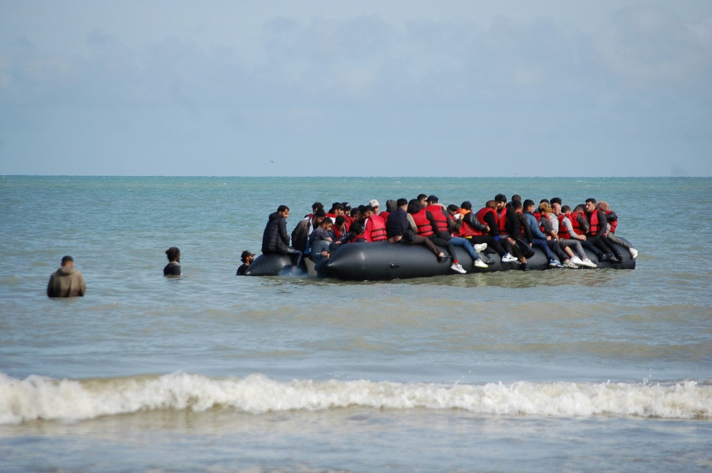 مهاجرون على متن قارب مطاطي قبل محاولتهم عبور المانش إلى بريطانيا من شمال فرنسا بتاريخ 18 تموز/يوليو 2023 (أ ف ب)   