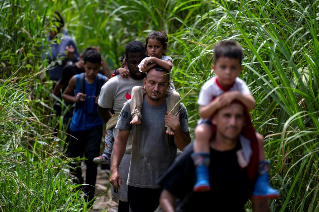 مهاجرون يحملون أطفالًا يسيرون عبر الغابة بالقرب من قرية باجو تشيكيتو، أول نقطة مراقبة حدودية لمقاطعة دارين في بنما، في 22 سبتمبر 2023 (أ ف ب)   