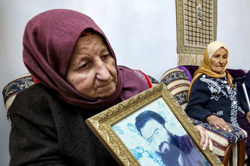عائشة والدة نائب حركة المقاومة الإسلامية حماس صالح العاروري تحمل صورته في منزل العائلة في قرية عارورة في شمال الضفة الغربية المحتلة في الثالث من كانون الثاني/يناير 2024 (ا ف ب)   