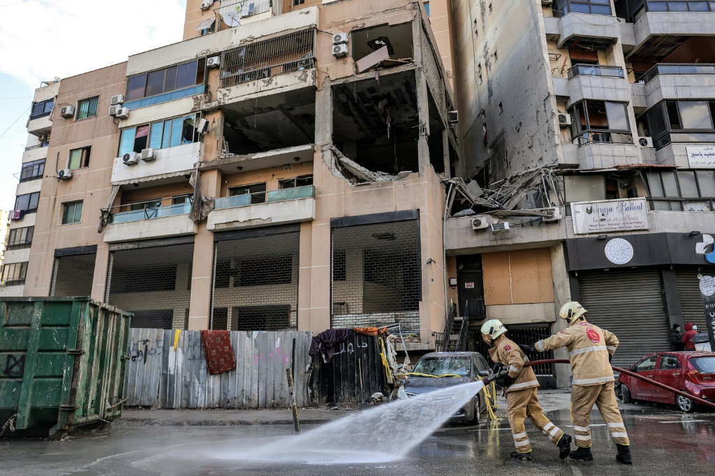 عناصر من الدفاع المدني أمام المبنى الذي أصيب بالضربة الإسرائيلية التي أودت بالقيادي في حماس صالح العاروري بضاحية بيروت الجنوبية في 3 كانون الثاني/يناير 2024 (ا ف ب)