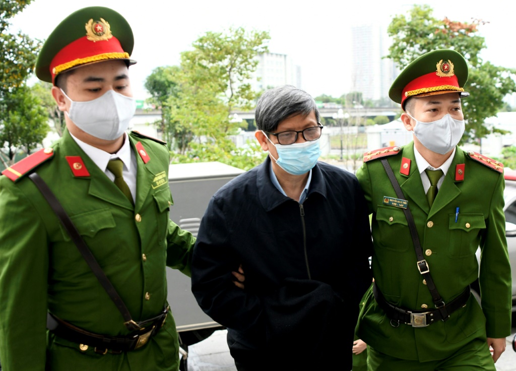 وزير الصحة الفيتنامي السابق نغوين ثانه لونغ يتوسط عنصرين من الشرطة لدى دخوله مبنى المحكمة في الثالث من كانون الثاني/يناير 2024 (ا ف ب)