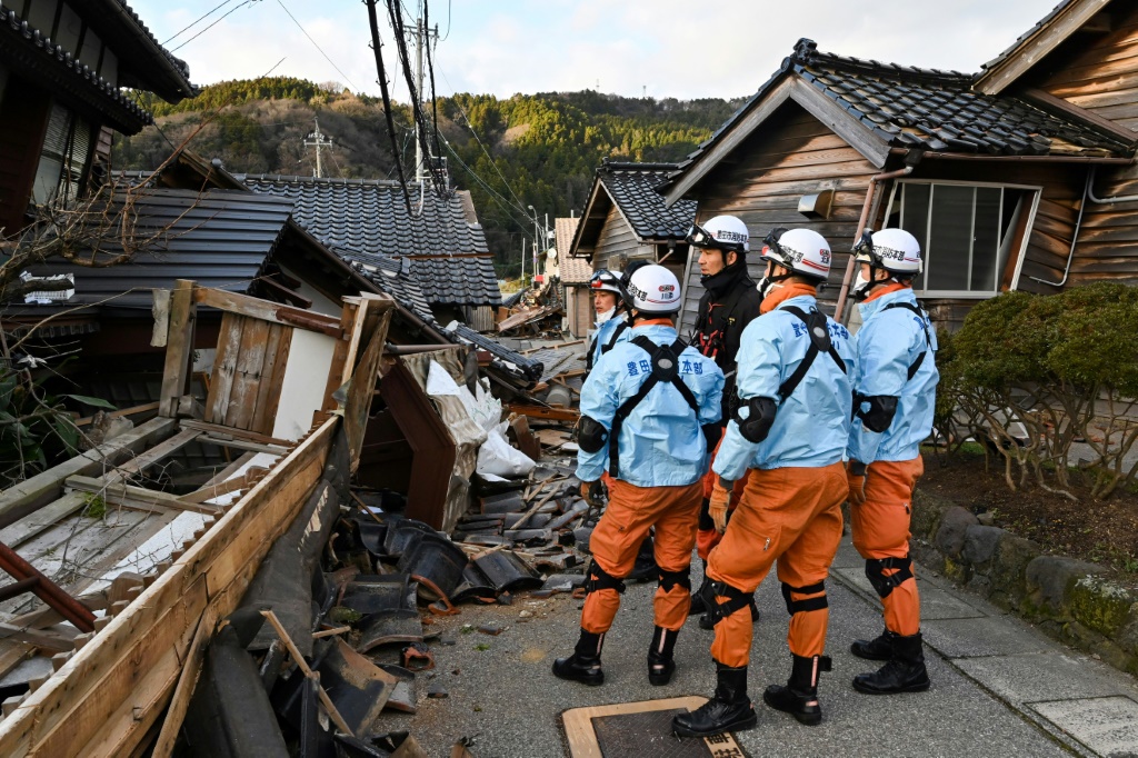 عمال انقاذ يتفقدون منازل هدمها الزلزال في وسط اليابان في مدينة واجيما في الثاني من كانون الثاني/يناير 2024 (ا ف ب)