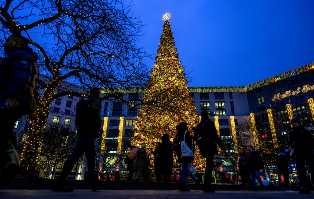 لقطة لأشخاص يمرون من أمام شجرة عيد الميلاد خارج مركز للتسوق في برلين بتاريخ 14 كانون الأول/ديسمبر 2023 (ا ف ب)