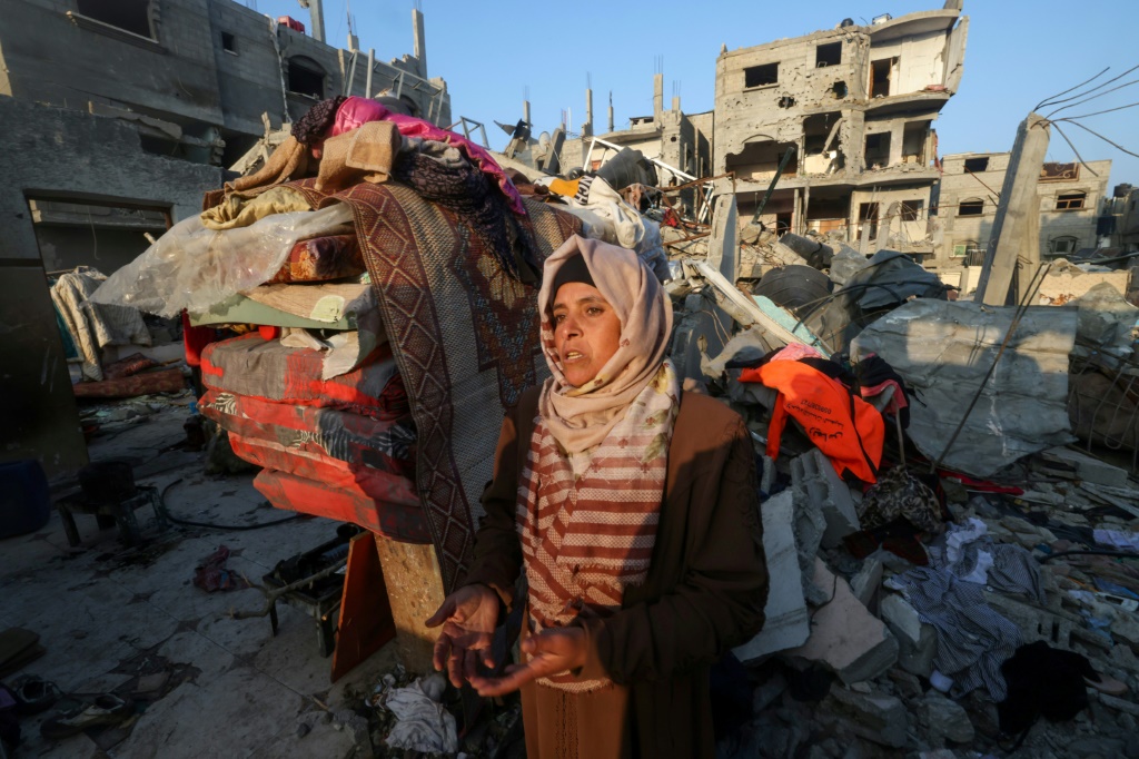 امرأة فلسطينية تقف أمام منزل دمره القصف الإسرائيلي في مخيم رفح للاجئين في جنوب قطاع غزة في 1 يناير 2024 (ا ف ب)