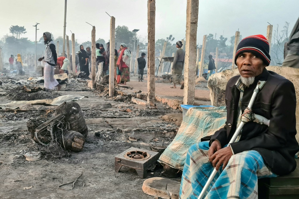 لاجئون من الروهينجا ينظرون بين أنقاض منازلهم التي تفحمت جراء حريق مدمر يوم الأحد (أ ف ب)   