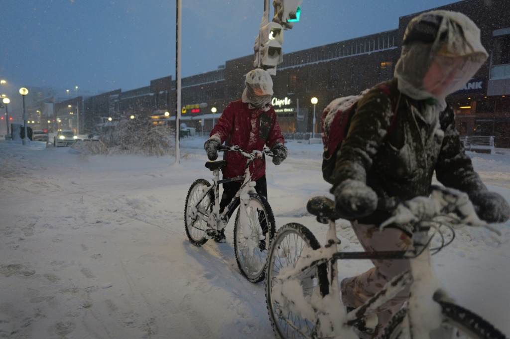 راكبو الدراجات يتنقلون على الرصيف المغطى بالثلوج في مدينة آيوا، آيوا (أ ف ب)   