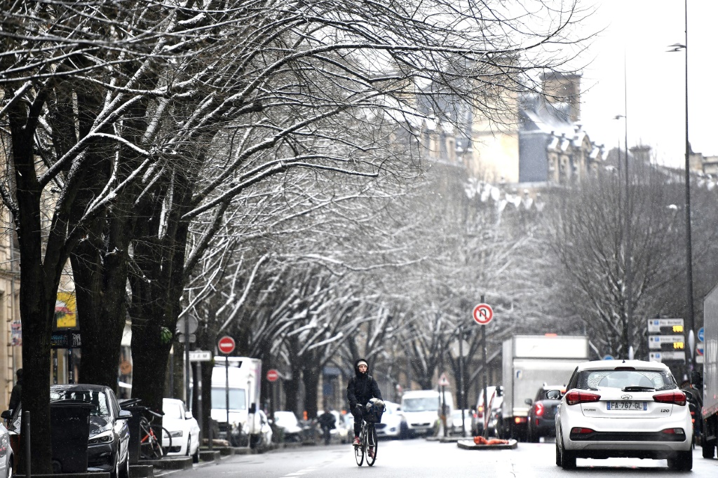 امرأة على دراجتها الهوائية خلال تساقط في أحد شوارع مدينة بوردو الفرنسية في جنوب غرب فرنسا في 10 كانون الثاني/يناير 2024. (ا ف ب)