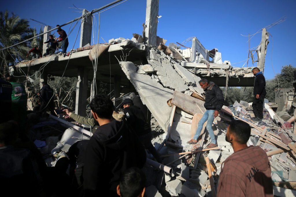 فلسطينيون يتفقدون أنقاض منزل في دير البلح بعد غارة إسرائيلية يوم الثلاثاء. (ا ف ب)