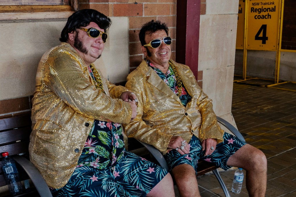 اثنان من مقلّدي إلفيس بريسلي ينتظران في محطة سيدني المركزية في 11 كانون الثاني/يناير 2024 القطار الذي يقلّ المعجبين بالنجم الراحل إلى مهرجان يخصص له في مدينة باركس الأسترالية.(ا ف ب)