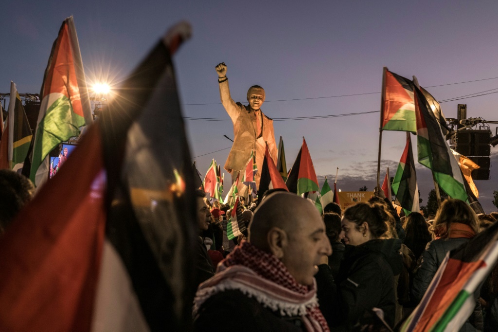 فلسطينيون يتجمعون حول تمثال رئيس جنوب أفريقيا الراحل نيلسون مانديلا في رام الله للاحتفال بقضية "إبادة جماعية" تاريخية رفعتها جنوب أفريقيا ضد إسرائيل في محكمة العدل الدولية (أ ف ب)