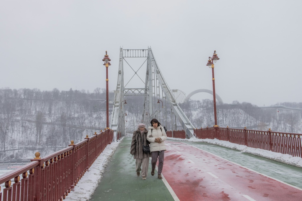 سكان يسيرون على جسر فوق نهر دنيبرو في كييف، في 14 كانون الثاني/يناير 2024، مع استمرار الحرب مع روسيا (ا ف ب)