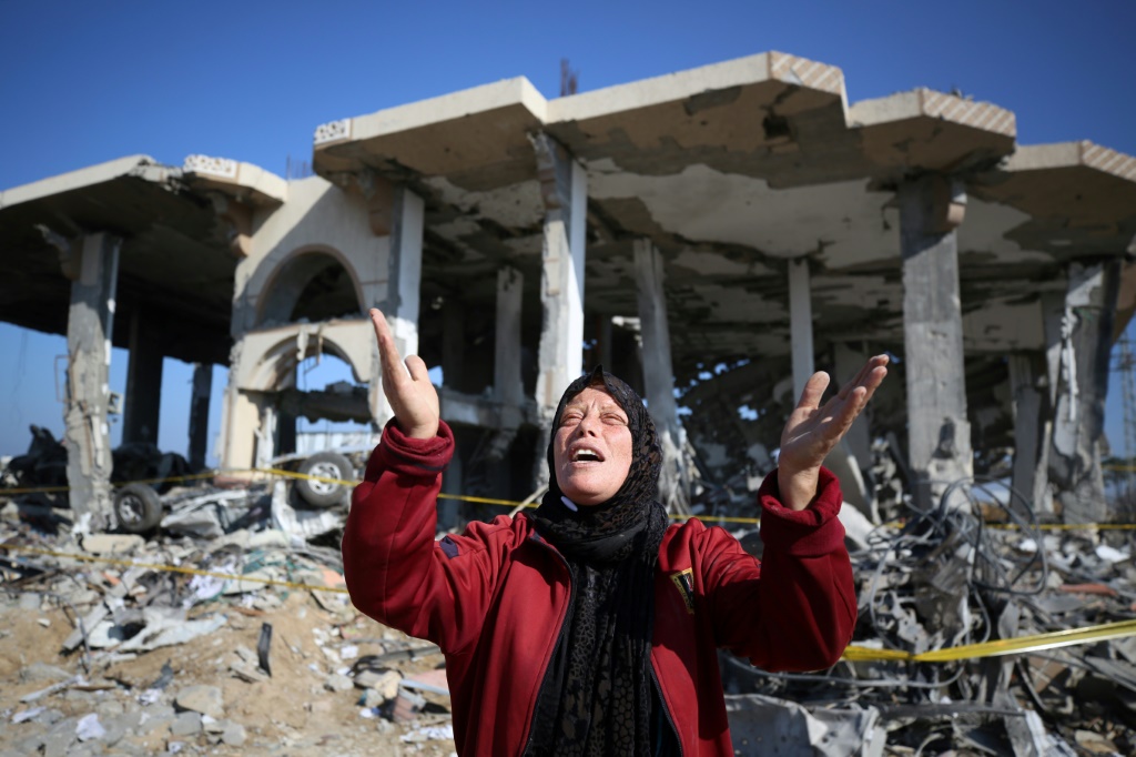 فلسطينية أمام مبنى دمّره قصف إسرائيلي في مخيم المغازي وسط فتاة قطاع غزة في 16 الثاني/يناير 2024. (ا ف ب)
