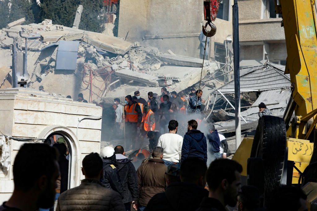 أهالي وفرق الإنقاذ أمام مبنى استهدف في غارة إسرائيلية، بحسب تقارير، في دمشق في 20 كانون الثاني/يناير 2024 (أ ف ب)   