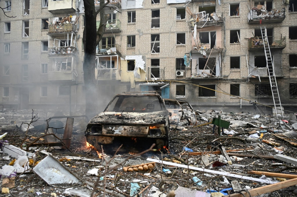 صورة التُقطت في 23 كانون الثاني/يناير 2024 تُظهر مركبات مدمّرة أمام مبنى سكني مدمّر جرّاء ضربة صاروخية في خاركيف . (ا ف ب)