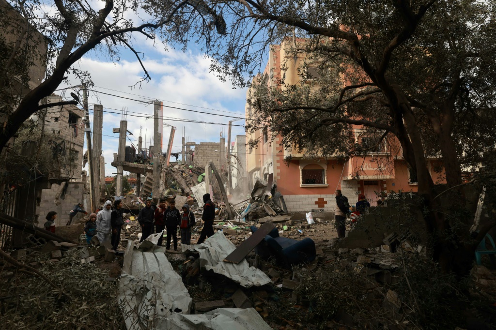 فلسطينيون يتفقدون أنقاض مبنى دمره القصف الإسرائيلي في رفح بجنوب قطاع غزة في 27 كانون الثاني/يناير 2024، فيما يتواصل القتال بين إسرائيل وحركة حماس المسلحة. (أ ف ب)   