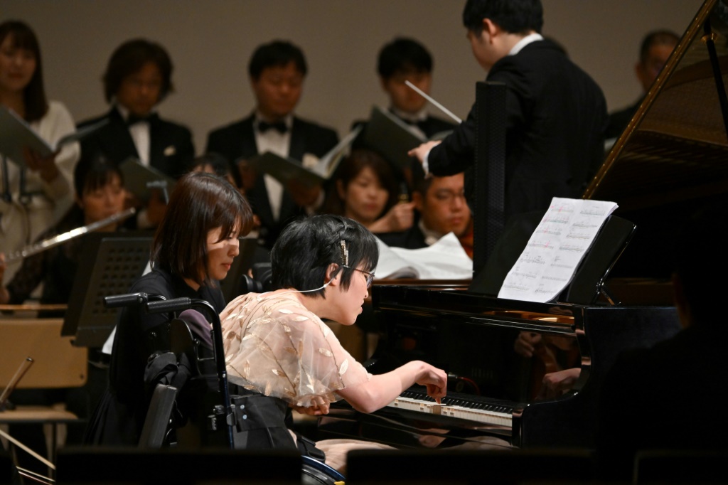 امرأة تعاني شللاً دماغياً تعزف بإصبع السبابة على بيانو يعمل بالذكاء الاصطناعي في طوكيو بتاريخ 21 كانون الأول/ديسمبر (ا ف ب)