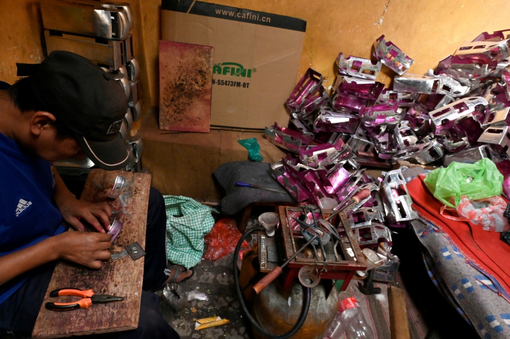 سجين في سجن سان بيدرو يصنع مجسيمات لسيارات معدنية ستُباع في سوق في لاباز، بتاريخ 18 كانون الثاني/يناير 2024 (ا ف ب)