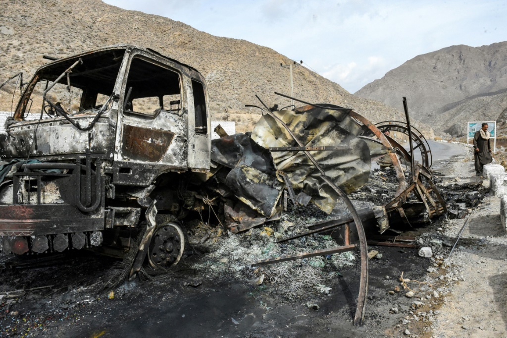 رجل يسير بجوار شاحنة أحرقها المسلحون خلال معركة استمرت لساعات في منطقة بولان بإقليم بلوشستان.(أ ف ب)   
