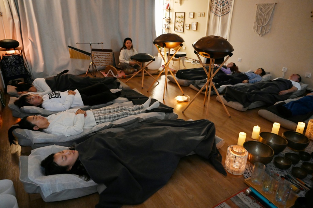 أشخاص ينامون خلال جلسة استرخاء في معهد "ييان" للعلاج الصوتي في بكين في الثامن من كانون الأول/ديسمبر 2023 (ا ف ب)