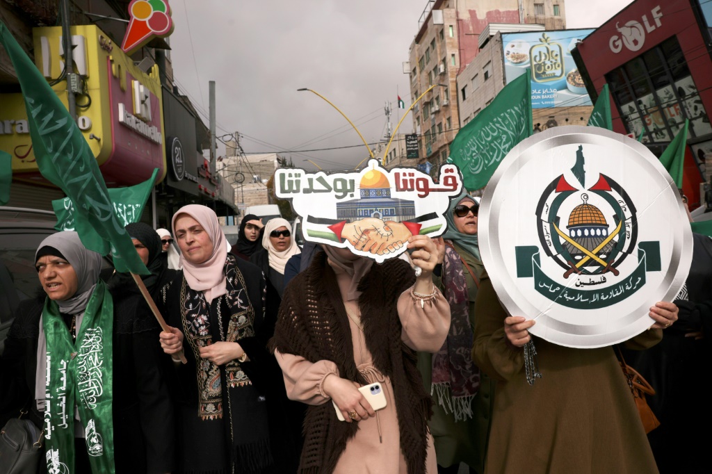 نساء فلسطينيات يحملن لافتات وأعلام حماس خلال تظاهرة في في مدينة الخليل بالضفة الغربية المحتلة في 3 كانون الثاني/يناير 2024 بعد مقتل نائب رئيس المكتب السياسي للحركة صالح العاروري في لبنان (ا ف ب)