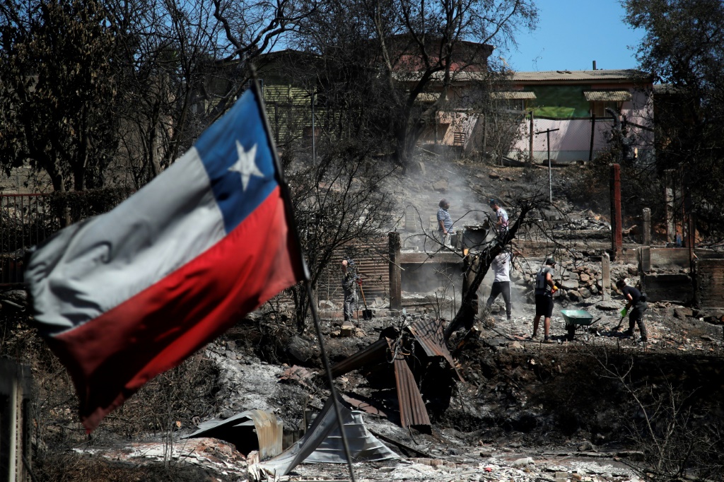 العلم التشيلي يرفرف فوق أنقاض منزل التهمته النيران في فيلا إندبندنسيا في فالباريسو في تشيلي في 5 شباط/فبراير 2024 (ا ف ب)