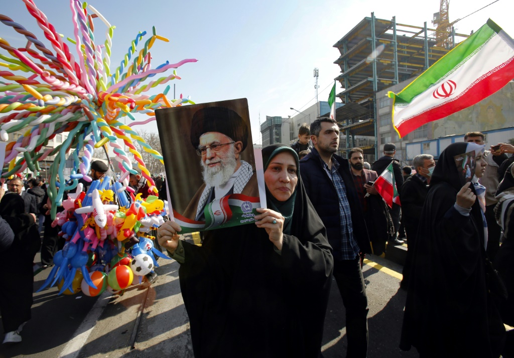امرأة ترفع صورة المرشد الأعلى الإيراني آية الله علي خامنئي، بينما يتجمع الناس للاحتفال بالذكرى الخامسة والأربعين للثورة الإسلامية في طهران في 11 فبراير 2024 (أ ف ب)   