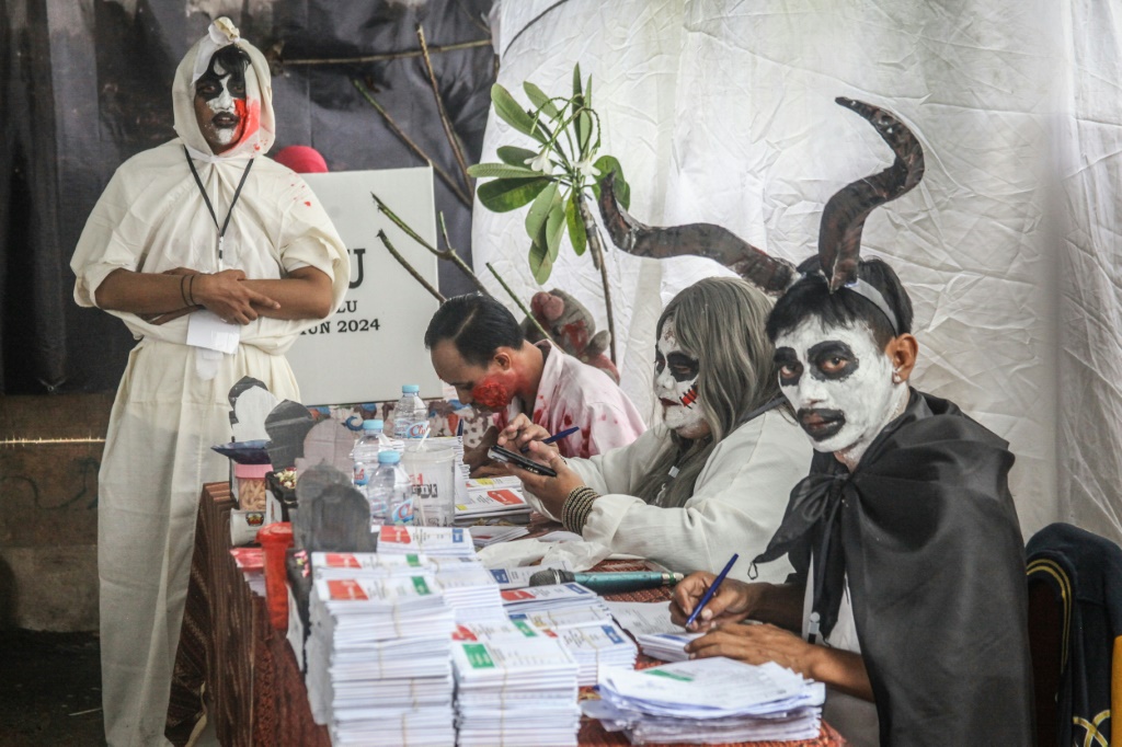 موظفون يرتدون أزياء رعب يعملون في مركز اقتراع خلال الانتخابات الرئاسية والتشريعية الإندونيسية في سورابايا. (ا ف ب)